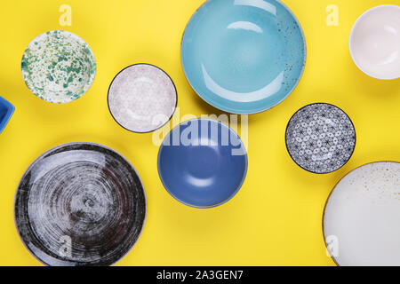Set of colorful modern porcelain plates and bowls on a yellow background. designer ceramic in different colors: blue, turquoise, grey and dark blue Stock Photo