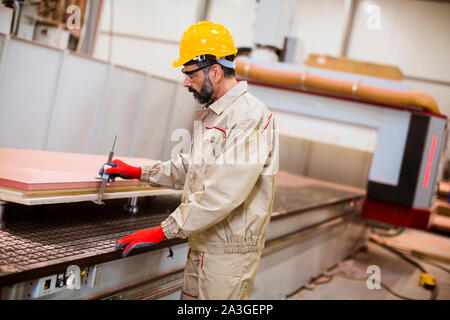 Portrait of senior man operating machine units in modern wooden factory standing by control panel Stock Photo
