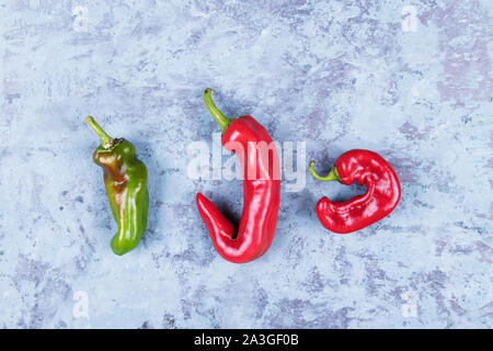 Three ugly red chili peppers on a blue grunge background minimal style