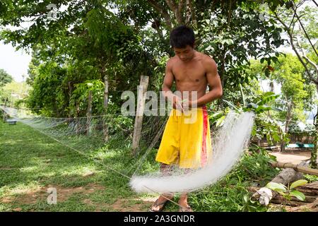 Philippines, Palawan, Malampaya Sound Protected Landscape and Seascape, boy repairing fishnet Stock Photo