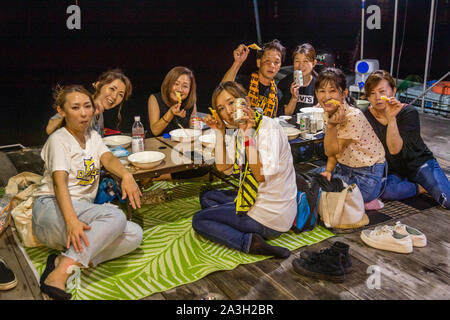 Good-humored company on the raft. Spearfishing at night is usually booked by groups. Takiya-ryo spearfishing on lake Hanama, Hamamatsu, Japan Stock Photo