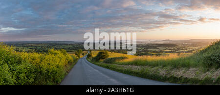 The road to Okeford Fitzpaine; dawn on the longest day in the Blackmore Vale, from Okeford Hill, Dorset, England, UK