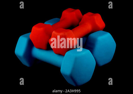 Blue and red dumbells isolated against a black background Stock Photo