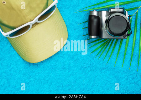 A cap with sunglasses and a camera lie on a towel. Stock Photo