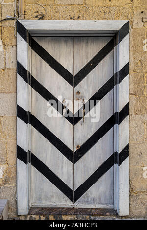 black and white diagonal stripes painted on an old wooden door, Malta. Stock Photo