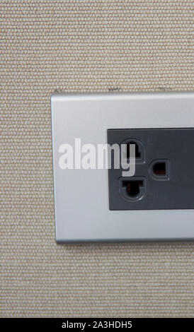 Grey universal electricity sockets plug on a yellow wall. Stock Photo