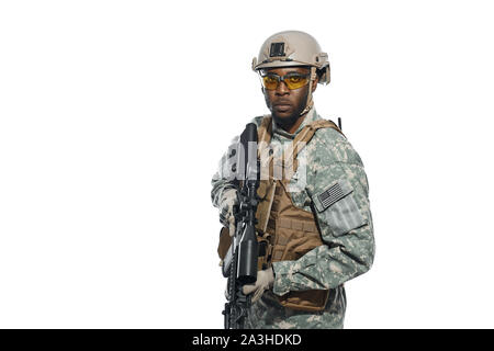 Front view of American soldier with weapon in hands and seriously looking at camera. African man wearing body armour and uniform waiting for instructions for battle. Concept of war and army. Stock Photo