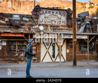 An old biker wearing a leather jacket and biker attire stands on the street in front of a store in Oatman, Arizona. Stock Photo