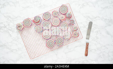 Step by step. Flat lay. Cooling freshly baked bake red, white, and blue pinwheel sugar cookies on a cooling rack. Stock Photo