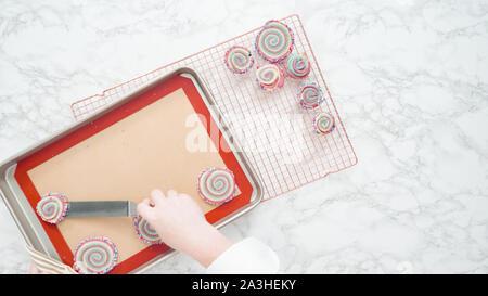 Step by step. Flat lay. Cooling freshly baked bake red, white, and blue pinwheel sugar cookies on a cooling rack. Stock Photo