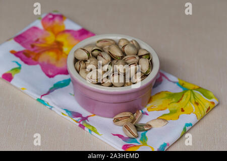 Pistachios in a pink bowl on floral napkin Stock Photo