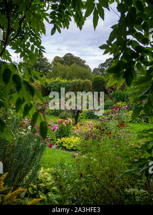 Chenies Manor Sunken Garden at Dahlia time, framed by a Wisteria keyhole. The ornamental pond features in the Sunken garden with the sculpture.. Stock Photo