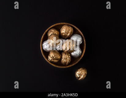 Painted golden and silver walnuts on wooden plate on black background Stock Photo