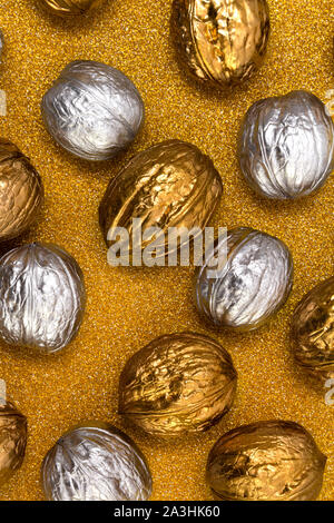 Painted golden and silver walnuts on glittering background Stock Photo