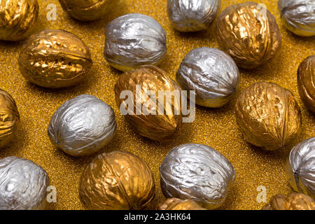 Painted golden and silver walnuts on glittering background Stock Photo