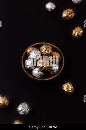 Painted golden and silver walnuts on wooden plate on black background Stock Photo
