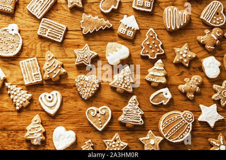 Ready Christmas gingerbread cookies in white sugar glaze lie on a wooden plane. Stock Photo