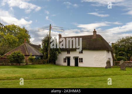 A white thatached cottage in the grounds of St James church, Avebury, Wiltshire, England, UK Stock Photo