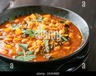 Bowl with a home made tomate and chickpea soup with malabar spinach. Stock Photo