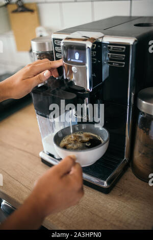 Young woman making coffee with milk from a espresso machine in t Stock Photo