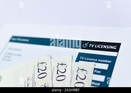Close up photo of UK TV license with 20 pound notes. TV Licensing for every household in the UK with TV. Stock Photo