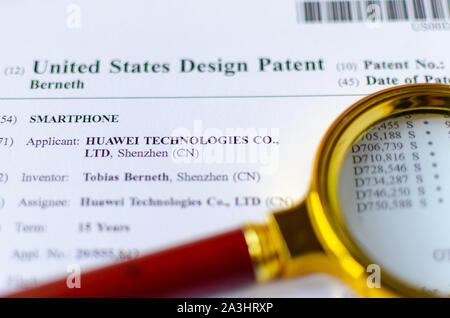 The close up photo of HUAWEI US patent and magnifying glass. Chinese technologies are under investigation. Stock Photo