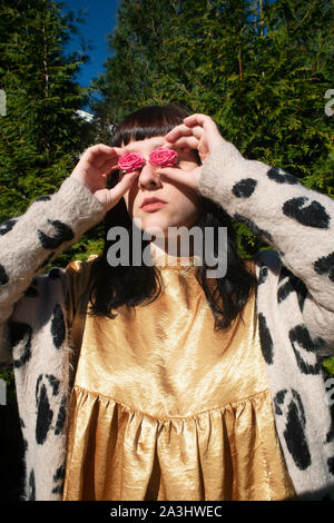 Half-Length Portrait of Young Adult Woman Holding Pink Roses to her Eyes Stock Photo