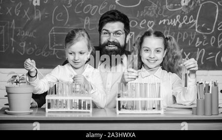 Man bearded teacher work with microscope and test tubes in biology classroom. School biology experiment. Explaining biology to children. How to interest children study. Fascinating biology lesson. Stock Photo