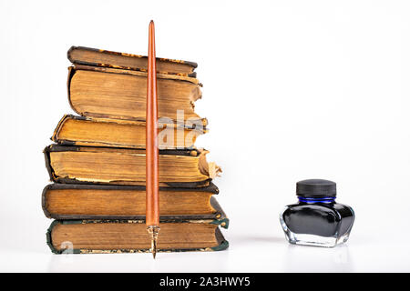 Old dusty books and writing nib on a bright countertop. Library items in old bindings. White background. Stock Photo