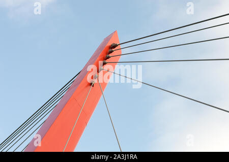 Cable bridge pole in red and cables in different angles on blue sky background Stock Photo