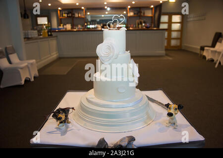 Tiered, iced wedding cake on a cake stand decorated ready to be cut by the bride and groom at the wedding reception Stock Photo