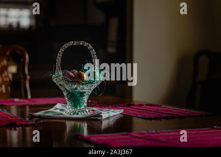 Easter eggs in crystal basket on dining room table in morning sunlight Stock Photo