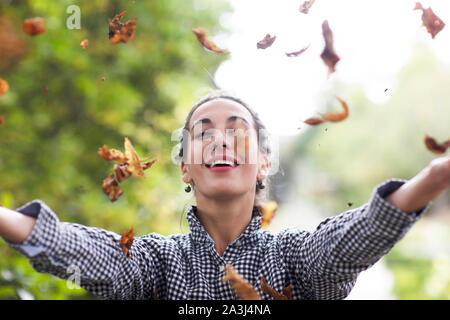 young woman throwing leafs in a garden Stock Photo