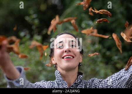 young woman throwing leafs in a garden Stock Photo