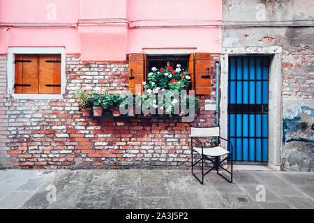 Old italian street with flowers in pots on rustic wall background. Travel background Stock Photo