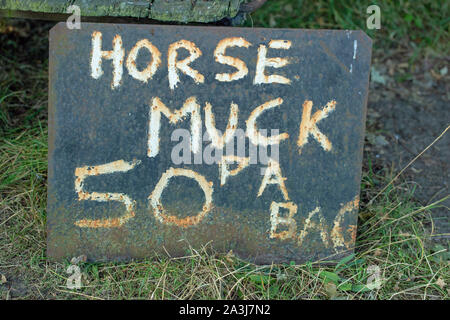 “Horse Muck”, hand painted onto a corroded metal sheet, and left by a Norfolk farm gate entrance. Manure for the roadside purchase, by passersby. Stock Photo