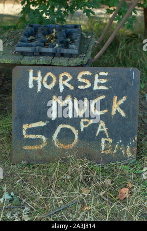 “Horse Muck”, hand painted onto a corroded metal sheet, and left by a Norfolk farm gate entrance. For sale to passing road traffic. Stock Photo