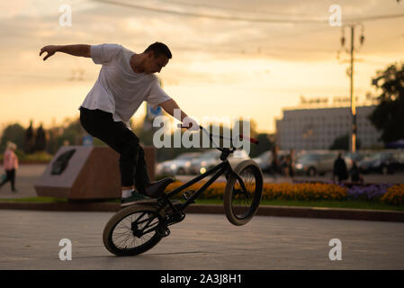 The guy performs a stunt on BMX, standing on the rear wheel. Stock Photo