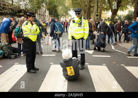 London, UK. 7th October 2019. Police officers arrest a 73 year old member of Extinction Rebellion on Millbank, after he refuses to stand up and move to the pavement, at the two week long protest in London. Credit: Joe Kuis / Alamy News Stock Photo