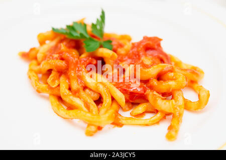 Traditional Tuscan pici pasta with tomato sauce, close-up Stock Photo