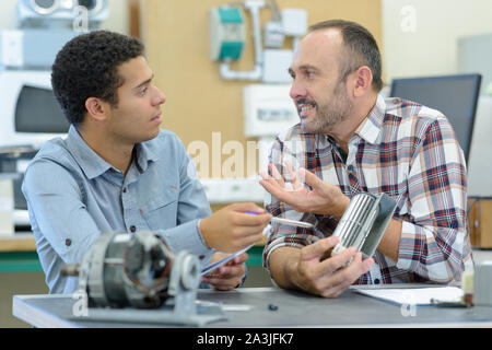 engineer and apprentice examining component in office Stock Photo