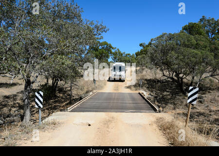 4WD Toyota Coaster Motorhome travelling on a dirt road over a cattle grid in the Outback near Ravenswood, Queensland, QLD, Australia Stock Photo