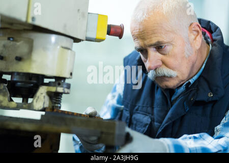 senior milling-machine operator works at machine Stock Photo