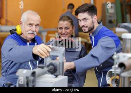 engineer and female apprentice measuring components in factory Stock Photo