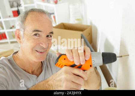 senior man using drill at home Stock Photo