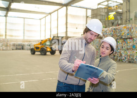 workers looking at clipboard in clean and tidy recycling center Stock Photo