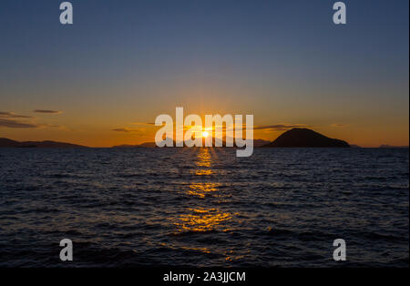 Panorama of sunset at Turgutreis, Turkey, Aegean Sea. Sun sets through the peak of Fork Island, and some other distant Greek islands. Stock Photo