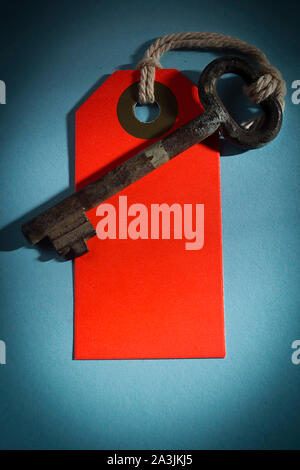 Old key with red tag on a blue table Stock Photo