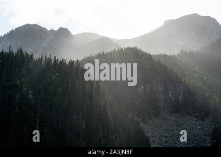 The sun shines through rain and clouds above Joffre Lake. Stock Photo