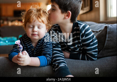 Brother kissing his little brother on the head on couch at home Stock Photo